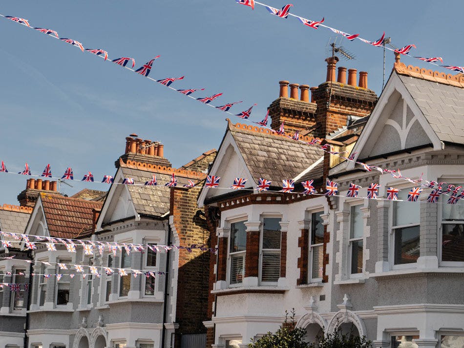 Image of Great Britain flag bunting tied across a row of houses on a street.