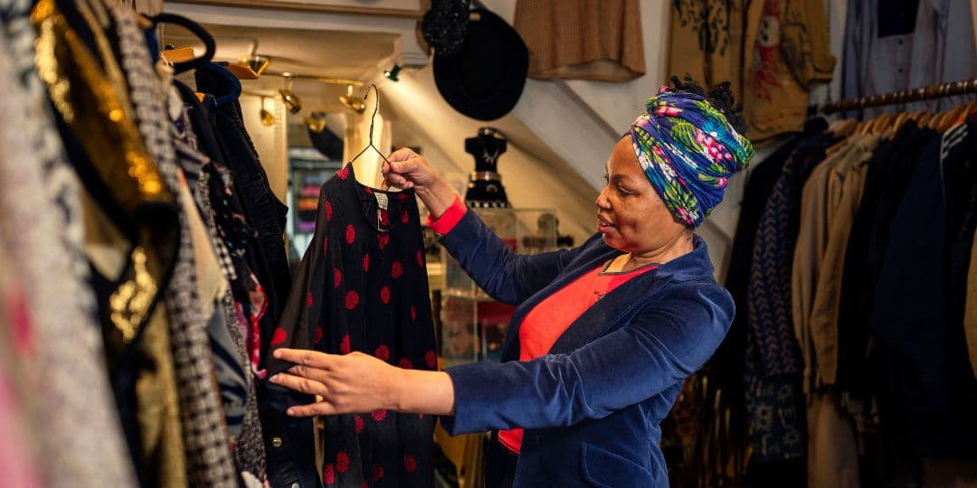 Image of a woman holding up a top on a coat hanger, working in her clothes shop.