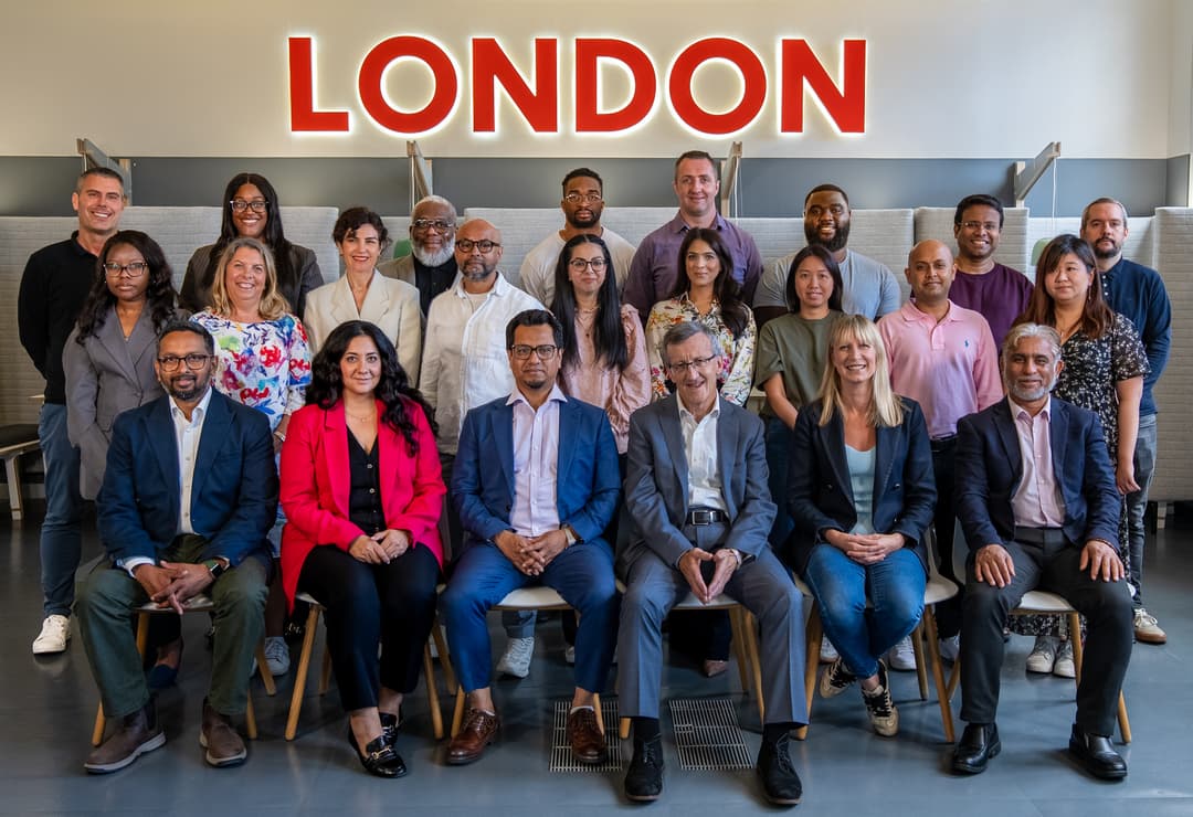 A diverse professional team posing in front of a historic building