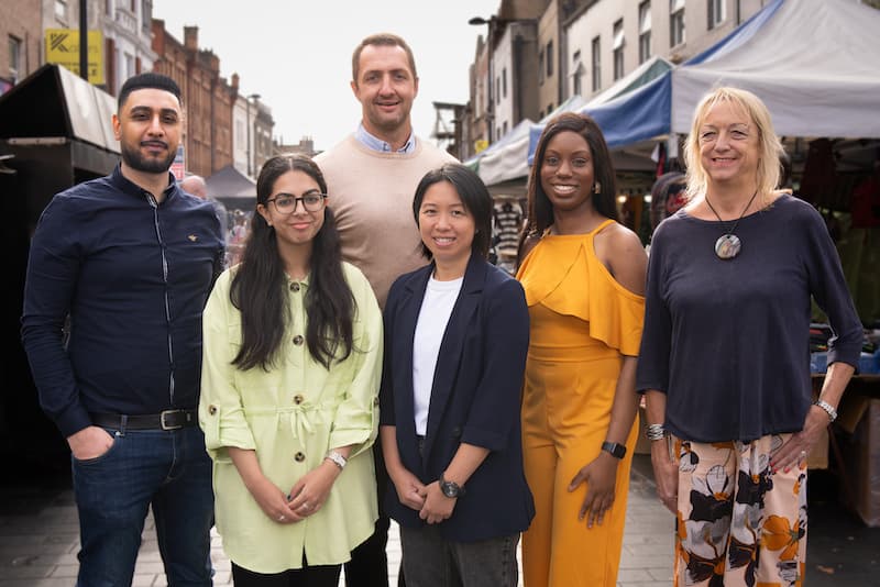 Image of a group of people standing in the street, smiling at the camera.